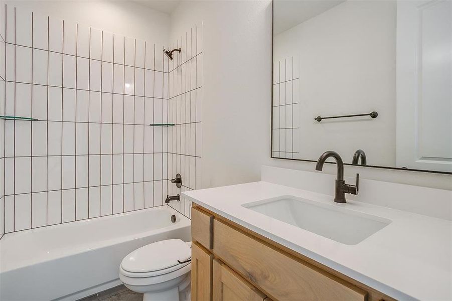 Full bathroom featuring toilet, tiled shower / bath combo, and vanity