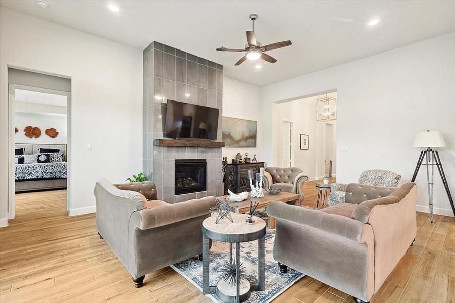 Living room featuring a tiled fireplace, light hardwood / wood-style flooring, and ceiling fan