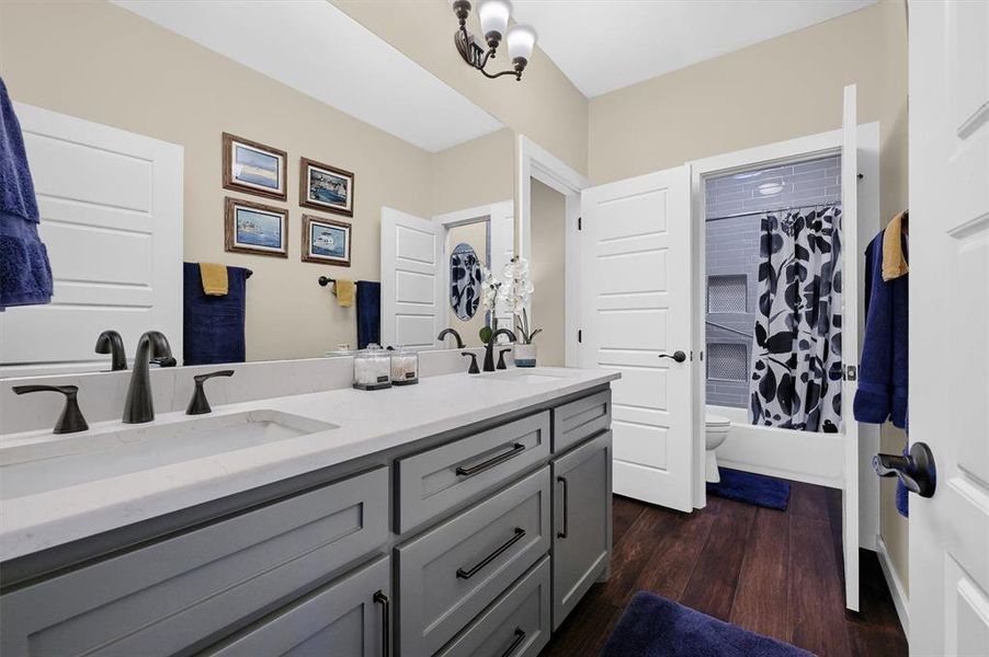 Full bathroom with shower / bath combination with curtain, an inviting chandelier, wood-type flooring, toilet, and vanity