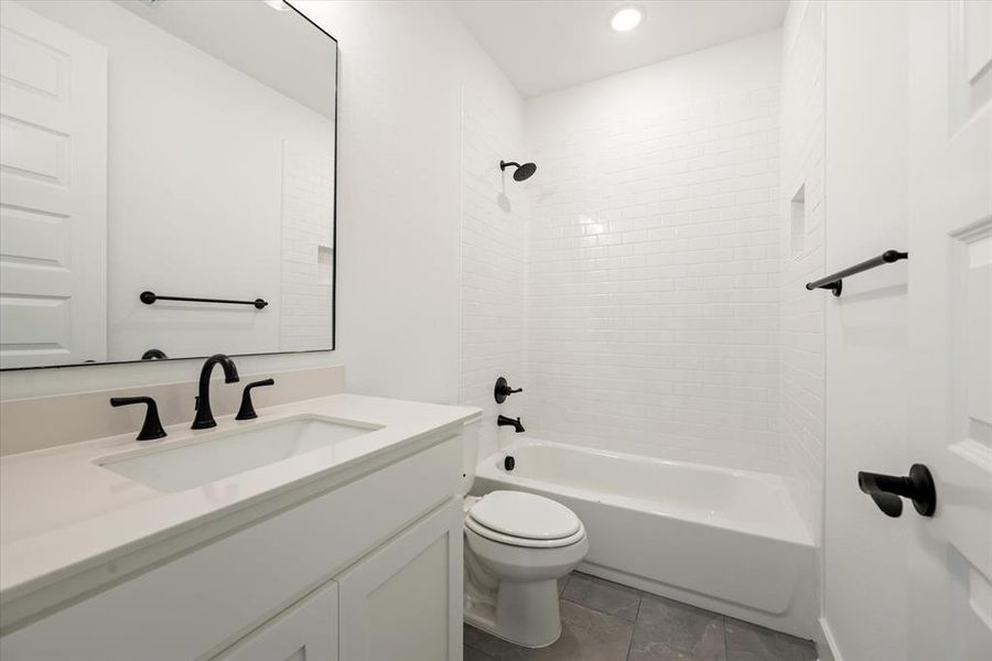 Full bathroom featuring tile patterned floors, toilet, vanity, and tiled shower / bath