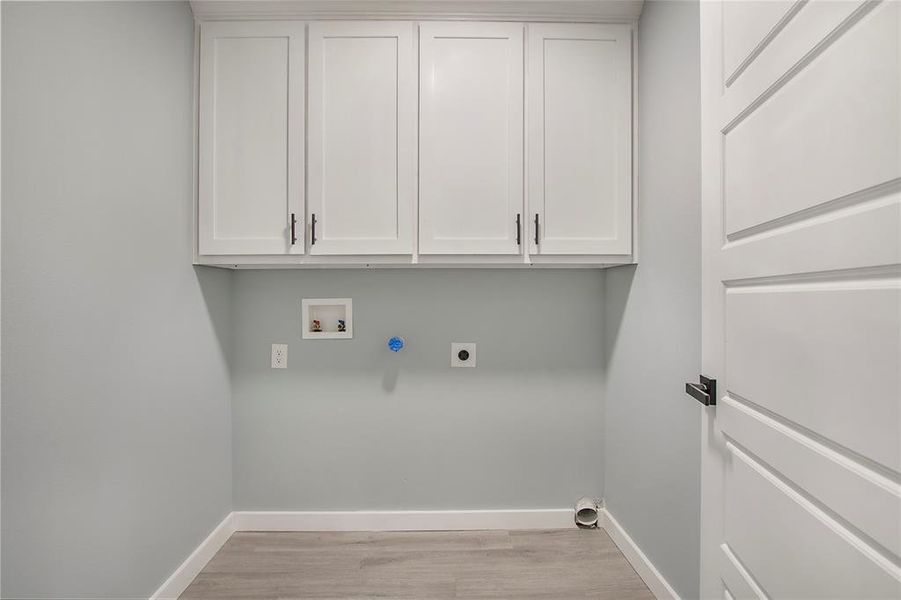 Laundry room with hookup for a washing machine, light hardwood / wood-style flooring, cabinets, and electric dryer hookup