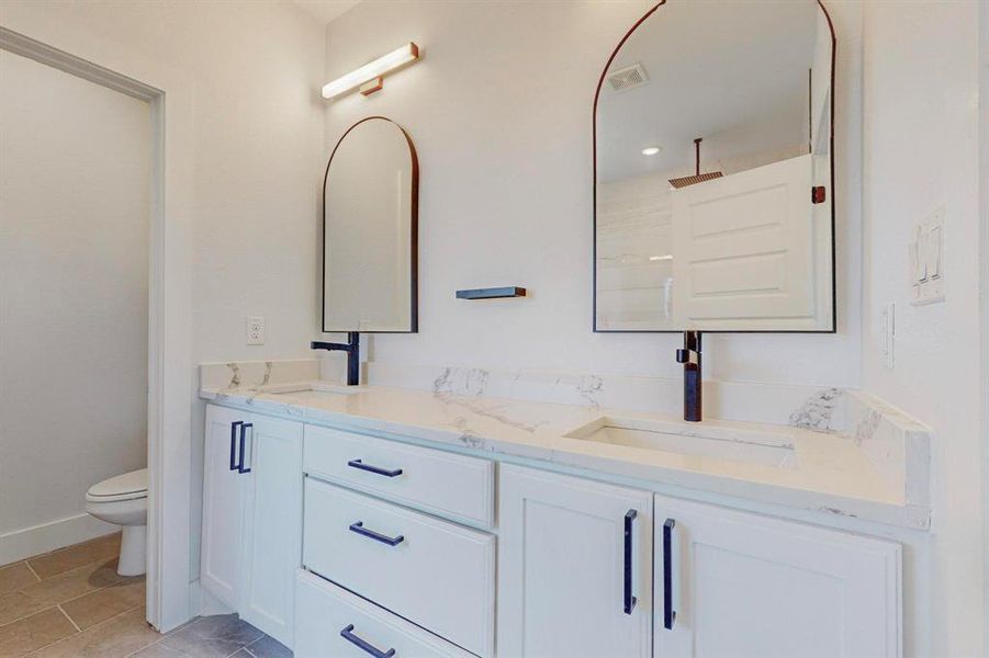 Bathroom featuring tile patterned floors, double vanity, and toilet