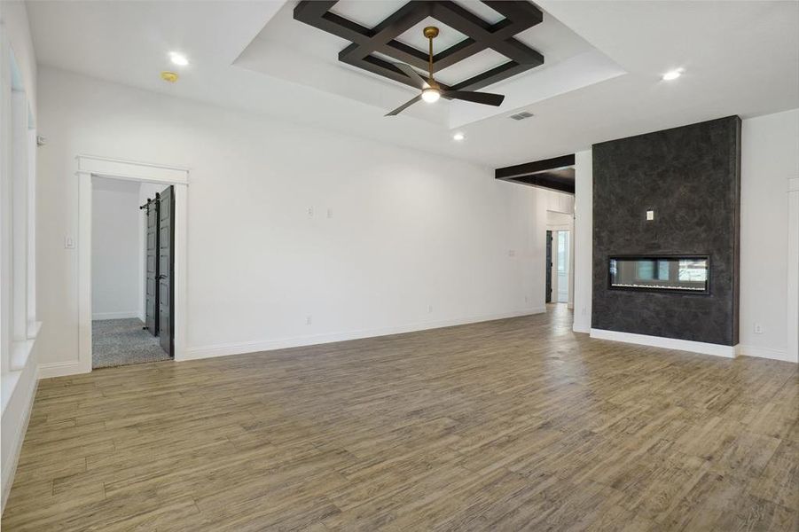 Unfurnished living room featuring hardwood / wood-style flooring, a fireplace, beamed ceiling, and coffered ceiling