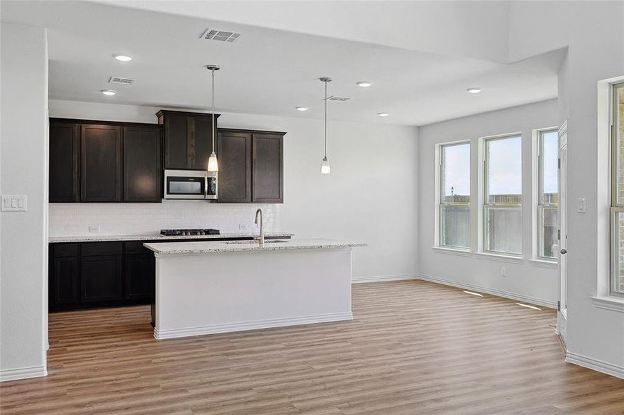 Kitchen featuring sink, a center island with sink, light hardwood / wood-style flooring, and backsplash