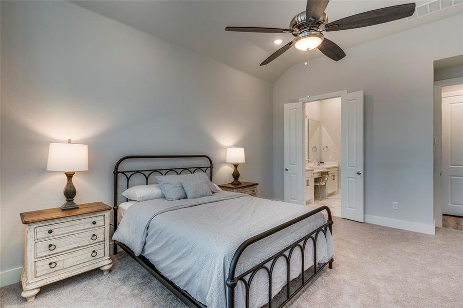 Bedroom with ensuite bath, lofted ceiling, light colored carpet, and ceiling fan