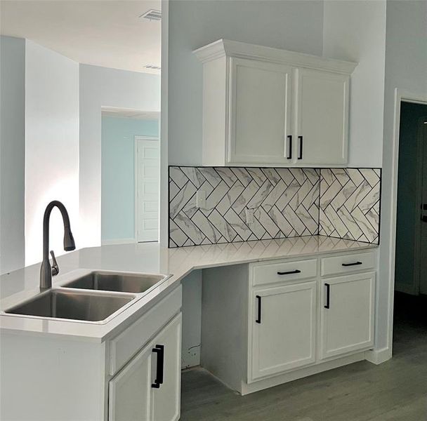 Kitchen featuring white cabinetry, decorative backsplash, sink, and light wood-type flooring