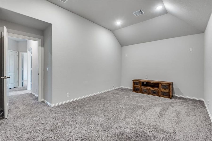 Empty room featuring light colored carpet and lofted ceiling