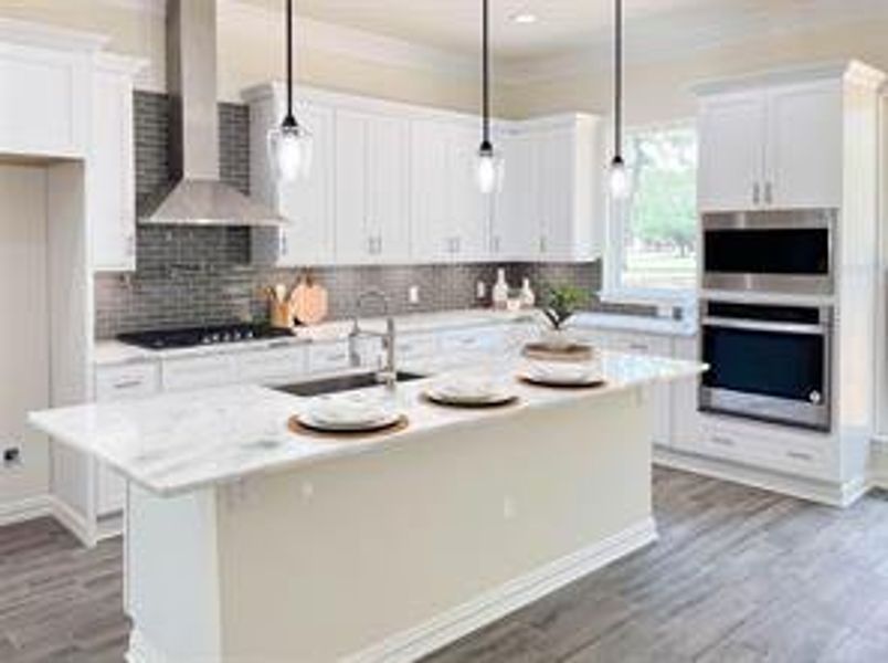 Kitchen featuring hanging light fixtures, a center island with sink, tasteful backsplash, white cabinetry, and wall chimney exhaust hood