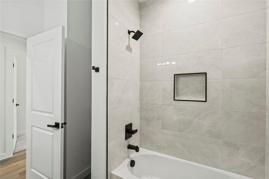 Bathroom featuring hardwood / wood-style flooring and tiled shower / bath