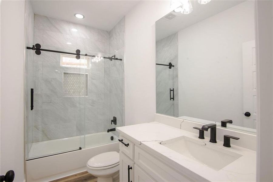 Full bathroom featuring shower / bath combination with glass door, vanity, toilet, and wood-type flooring