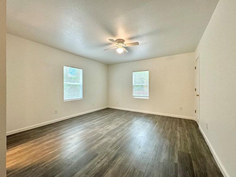 Unfurnished room with dark hardwood / wood-style flooring, ceiling fan, and a textured ceiling