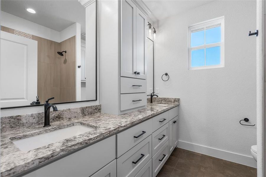 Secondary bathroom offers double vanities and linen cabinet.