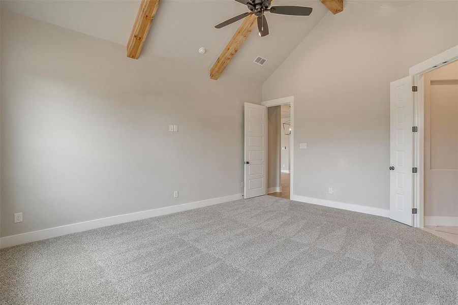 Unfurnished room featuring beamed ceiling, high vaulted ceiling, carpet floors, and ceiling fan