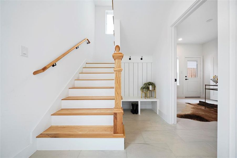 The picturesque view reveals a classic wood staircase and a convenient mud section, while also offering a tantalizing glimpse into the inviting first-floor bedroom, harmoniously blending style and practicality.