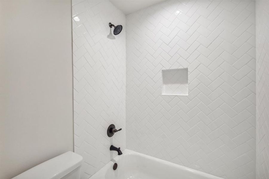 Bathroom with tiled shower / bath combo and toilet