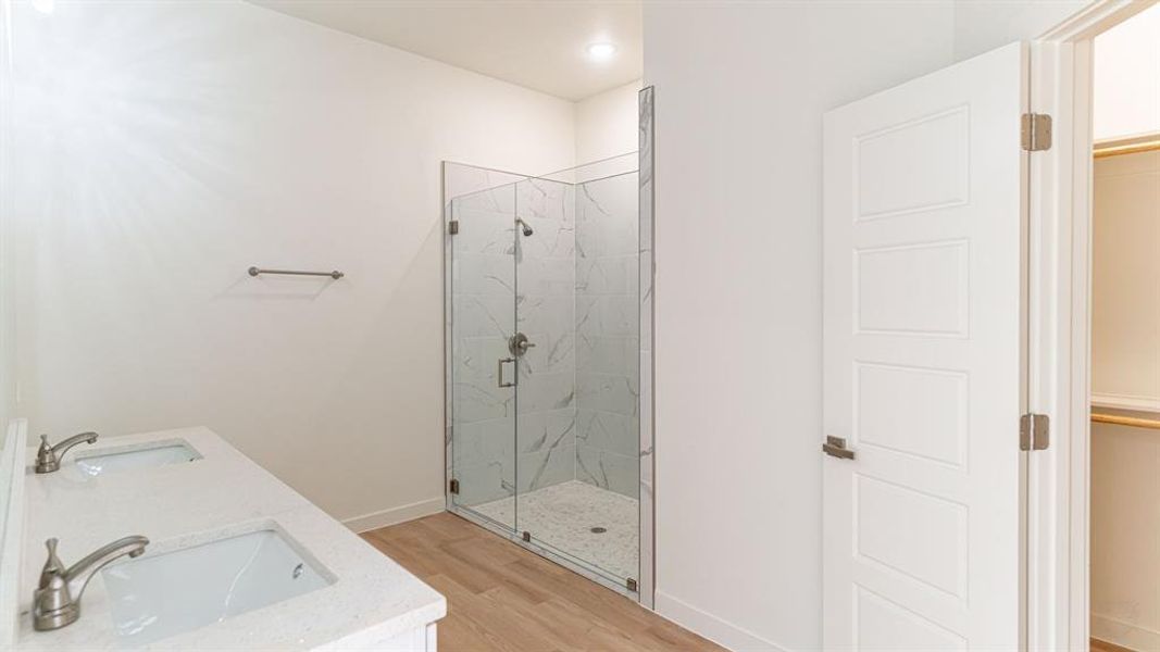 Primary bath with dual sinks and glass tiled shower