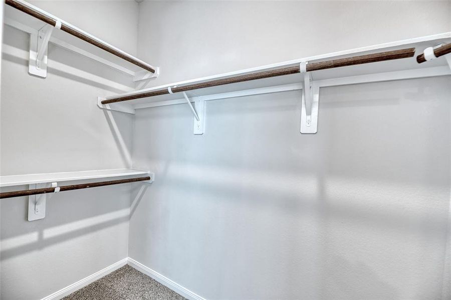 Additionally, the primary bathroom features a spacious walk-in closet equipped with multiple racks, offering ample storage space for organizing clothes, accessories, and personal items with ease.