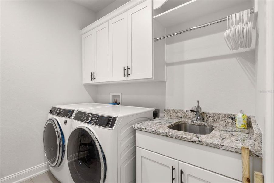 Laundry Room features a Utility Sink, Quartz Countertop and Additional Cabinetry