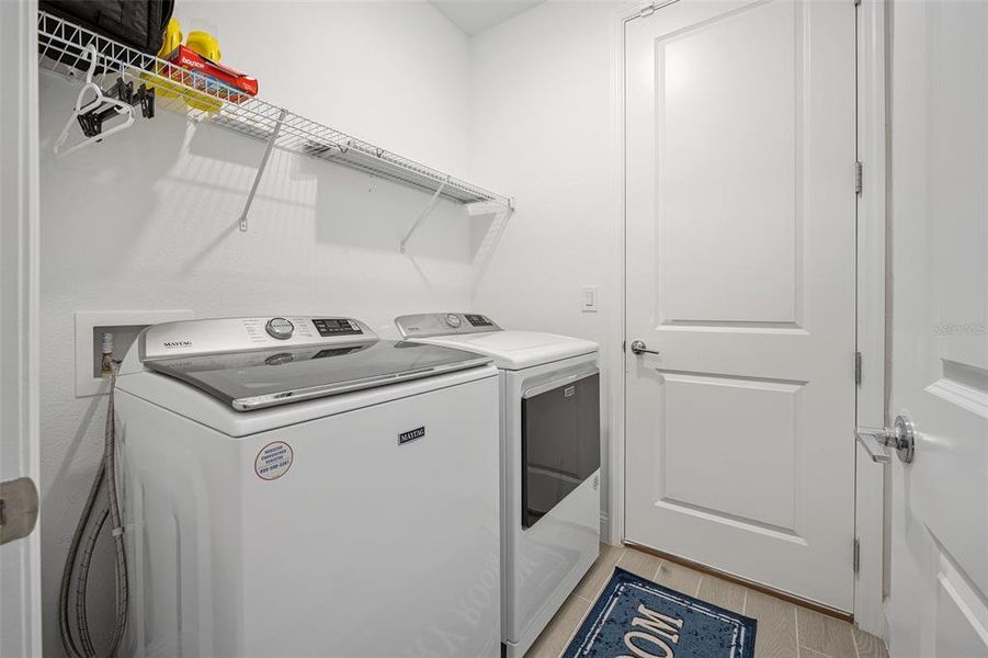 Laundry room with shelving above