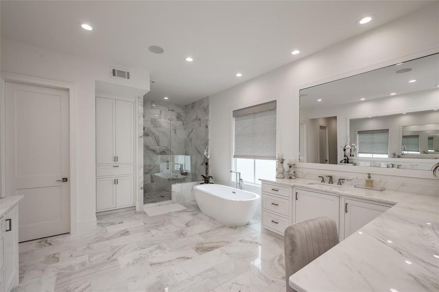 The luxurious primary bath offers a walk-in shower, and bath, as well as two sinks, vanity, and plentiful storage.