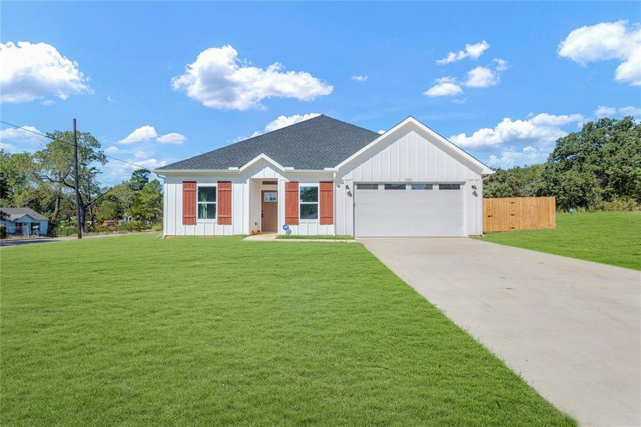 View of front of property featuring a garage and a front lawn