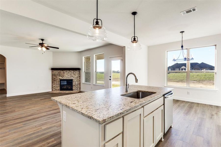 Kitchen featuring hardwood / wood-style flooring, plenty of natural light, a kitchen island with sink, and sink