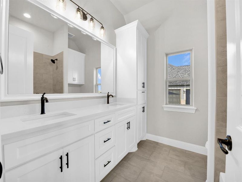 Bathroom with dual sinks, tile floors, and large vanity