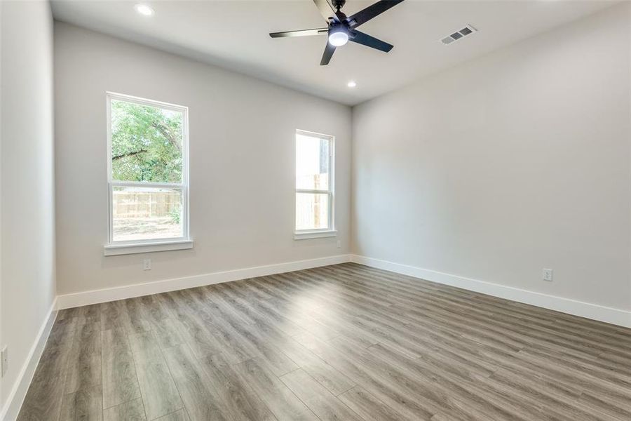 Unfurnished room with a healthy amount of sunlight, wood-type flooring, and ceiling fan