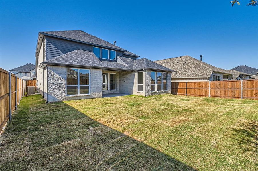 Rear view of house featuring a patio, a lawn, and central AC unit