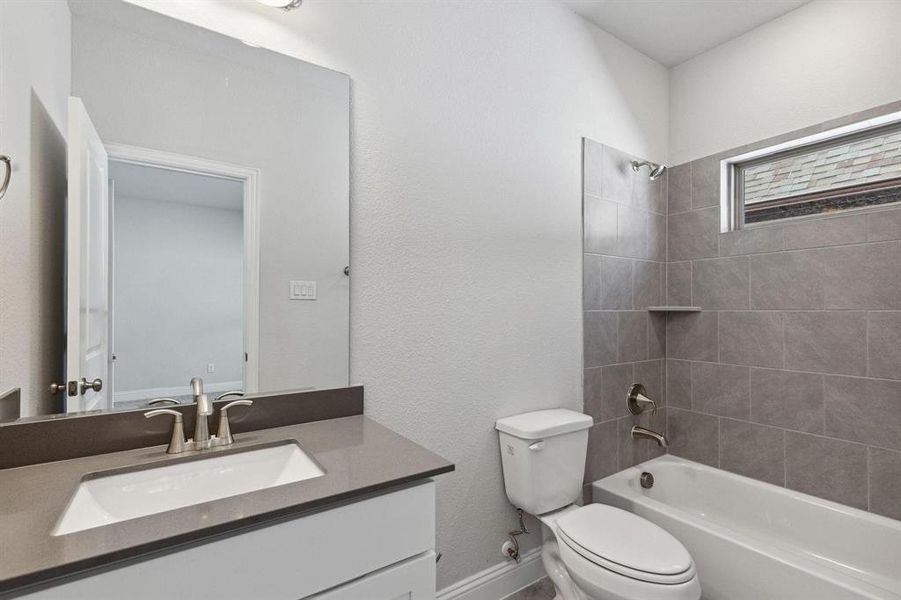 Full bathroom featuring tiled shower / bath, vanity, and toilet