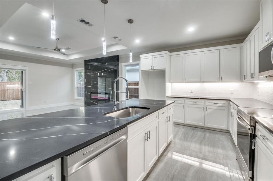 Kitchen featuring hanging light fixtures, appliances with stainless steel finishes, sink, and white cabinets