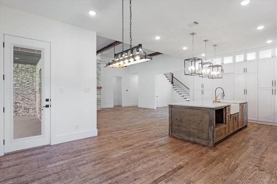 Kitchen with pendant lighting, a kitchen island with sink, hardwood / wood-style flooring, and sink