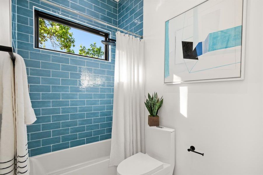 The shared jack-n-jill water closet provides the commode and a darling shower/tub combo with colorful subway tile backsplash and clerestory window.