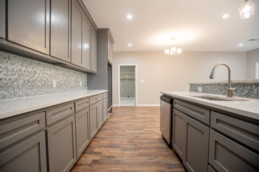 Kitchen with tasteful backsplash, dishwasher, dark hardwood / wood-style floors, decorative light fixtures, and sink