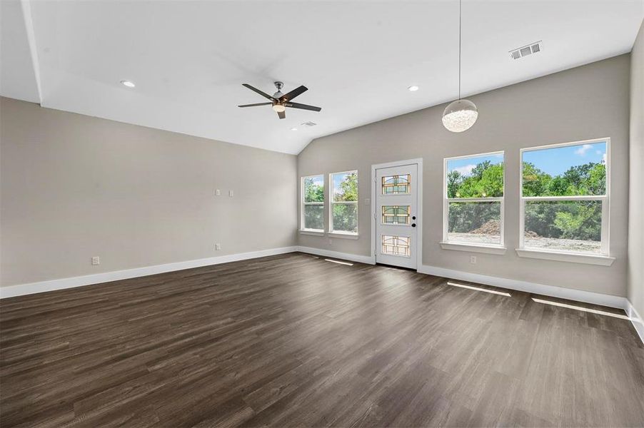 Unfurnished living room with dark hardwood / wood-style floors, vaulted ceiling, and ceiling fan