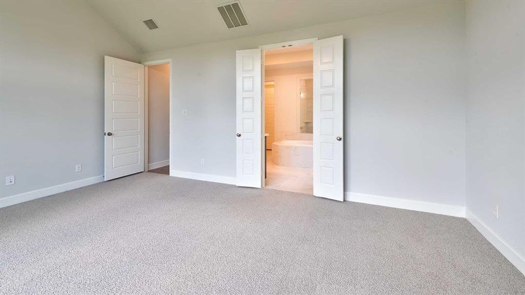 Unfurnished bedroom featuring lofted ceiling, carpet, and ensuite bath