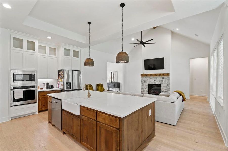 Kitchen with white cabinets, a fireplace, appliances with stainless steel finishes, sink, and a kitchen island