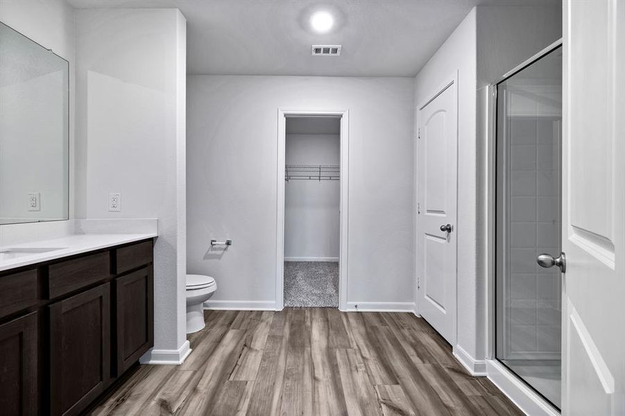 Bathroom with walk in shower, toilet, hardwood / wood-style floors, and vanity