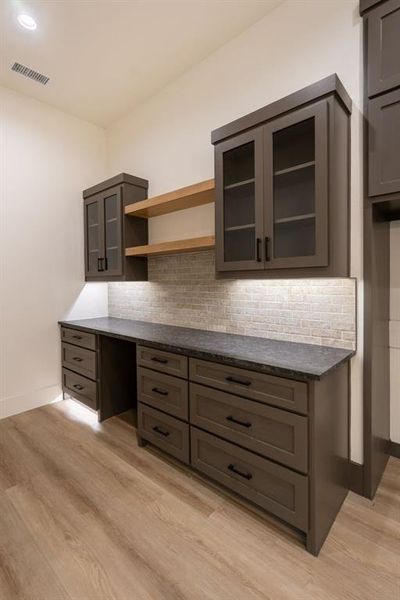 Kitchen featuring dark stone countertops, light wood-type flooring, and tasteful backsplash