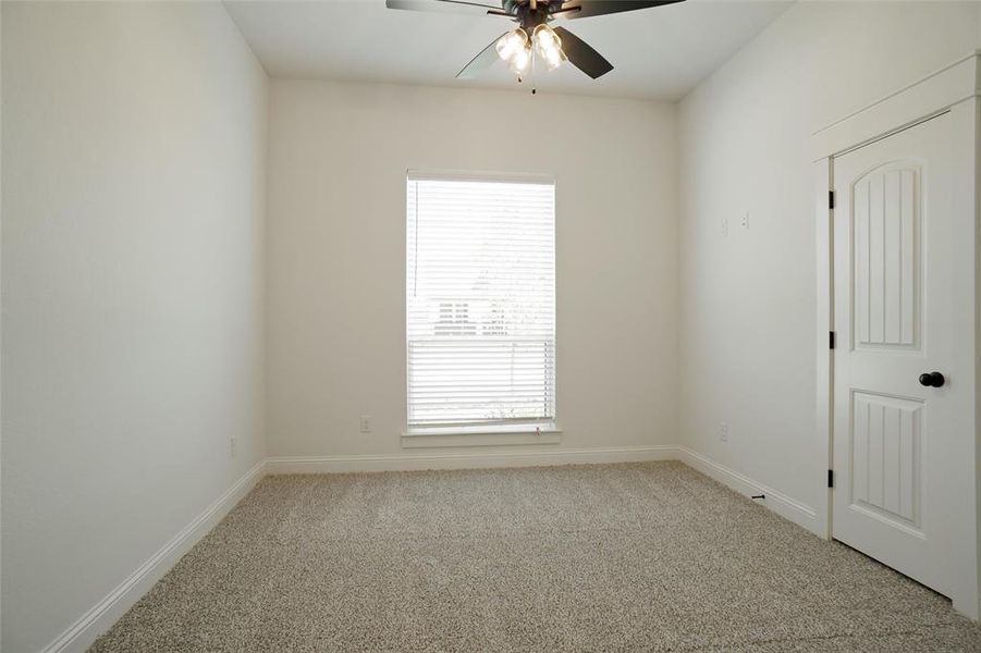 Carpeted empty room featuring ceiling fan