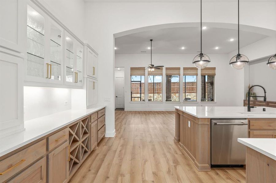 Kitchen with white cabinetry, hanging light fixtures, sink, dishwasher, and light hardwood / wood-style floors