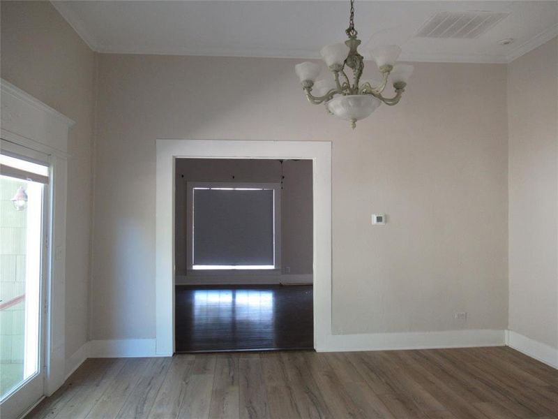 Unfurnished dining area with hardwood / wood-style flooring, crown molding, a chandelier, and a healthy amount of sunlight