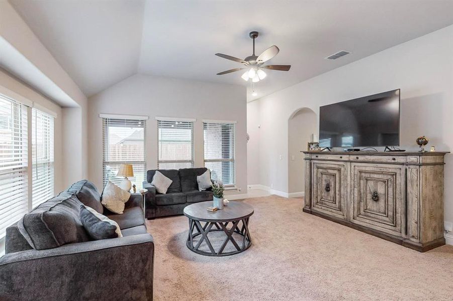 Living room with lofted ceiling, light carpet, and ceiling fan