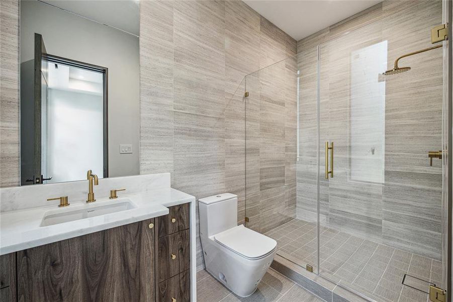 This bathroom offers the convenience of a walk-in shower with seamless glass doors and Signature Hardware shower trim kit, along with Duravit under-mount bathroom sink and commode, all accented by Signature Hardware widespread sink faucet in polished chrome and a meticulously crafted shower drain, ensuring both style and functionality for your guests' comfort.