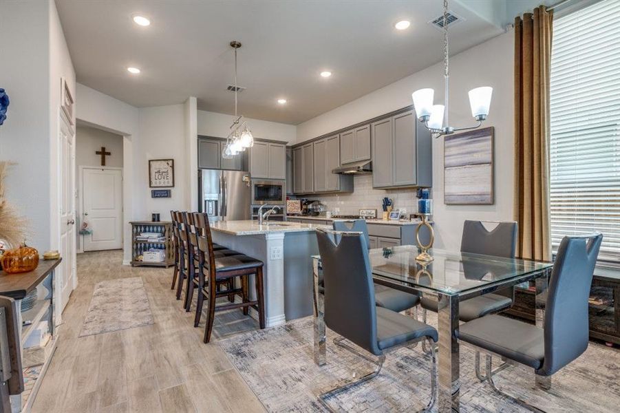 Kitchen with decorative light fixtures, stainless steel appliances, and gray cabinetry