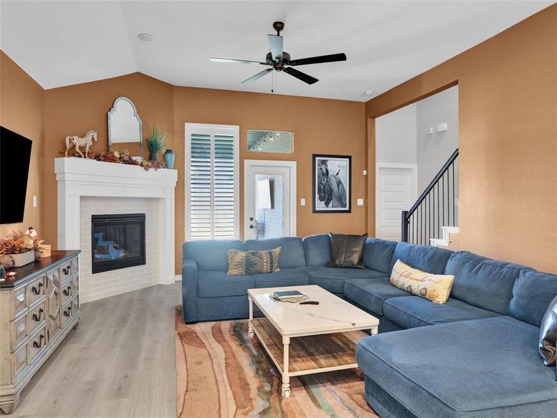 Spacious living room with gas fireplace and plantation shutters leading to a covered patio and backyard.