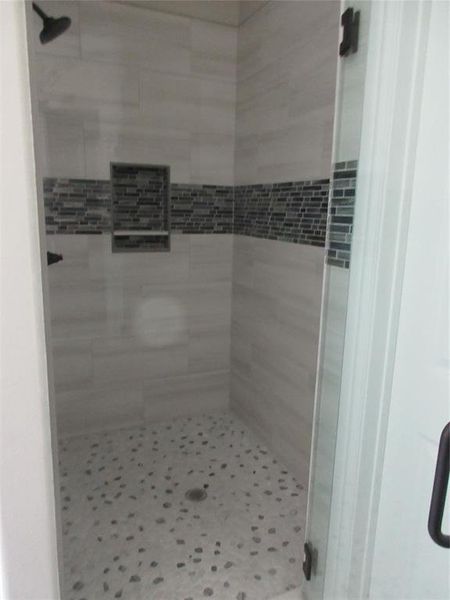 Bathroom with tiled shower and tile patterned flooring
