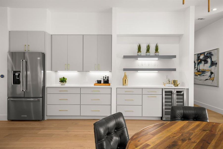 The kitchen provides a chef's quantity of cabinetry storage and counter space plus a bonus buffet/dry bar with a wine fridge and floating shelving.