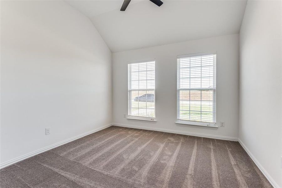 Carpeted spare room with ceiling fan and lofted ceiling