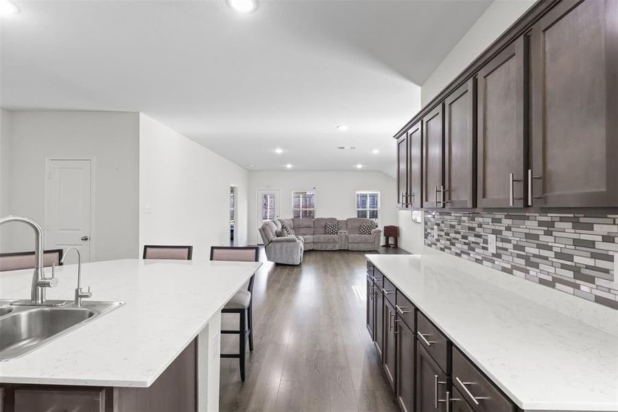 Kitchen featuring a kitchen bar, dark hardwood / wood-style flooring, a kitchen island with sink, and sink